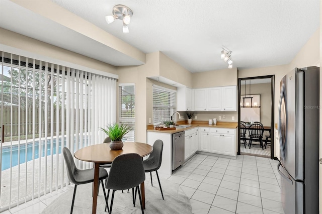 kitchen featuring white cabinetry, sink, light tile patterned floors, and appliances with stainless steel finishes