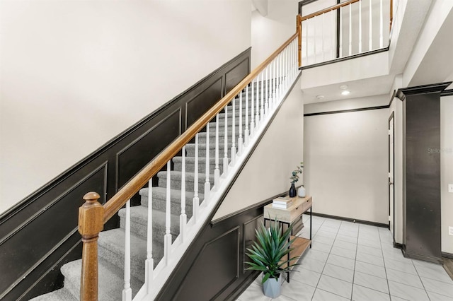 stairs featuring tile patterned floors and a high ceiling