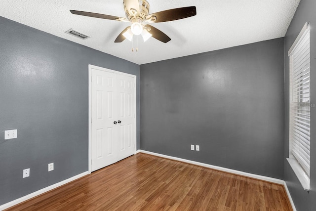 empty room with wood-type flooring, a textured ceiling, and ceiling fan