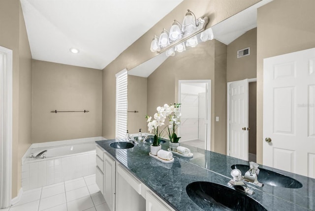 bathroom featuring tile patterned flooring, vanity, and tiled bath