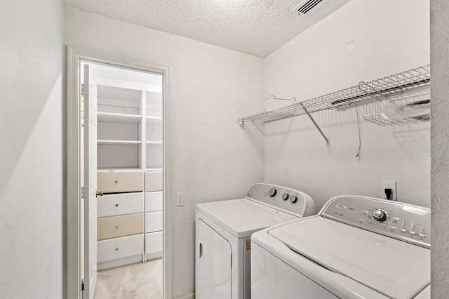 clothes washing area featuring independent washer and dryer, a textured ceiling, and light colored carpet