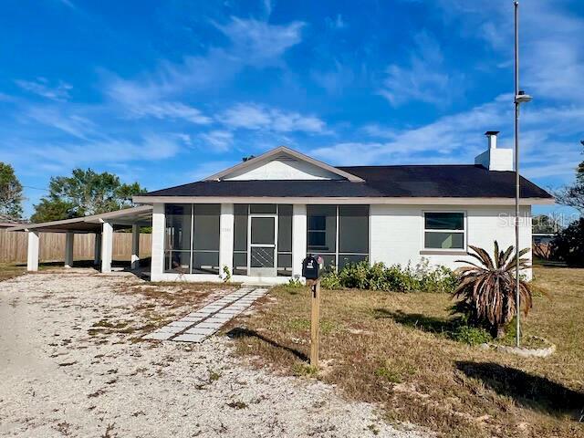 rear view of property with a carport and a lawn