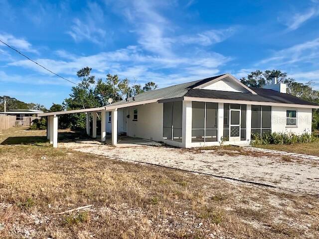 back of property featuring a carport and a sunroom