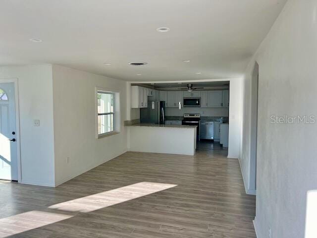 kitchen featuring black fridge, dark hardwood / wood-style flooring, range with electric stovetop, kitchen peninsula, and white cabinets