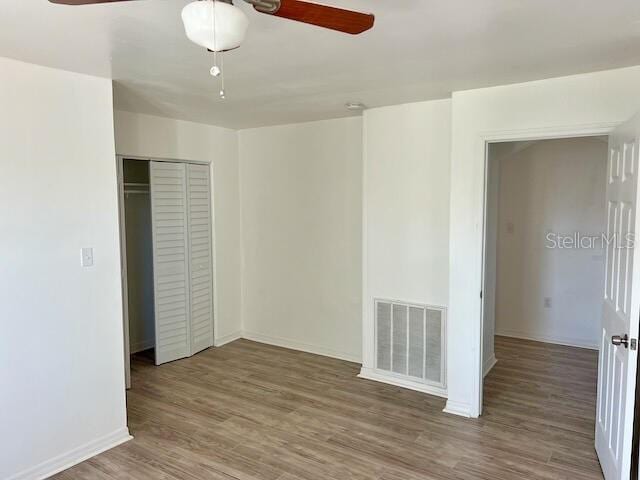 unfurnished bedroom with ceiling fan, wood-type flooring, and a closet