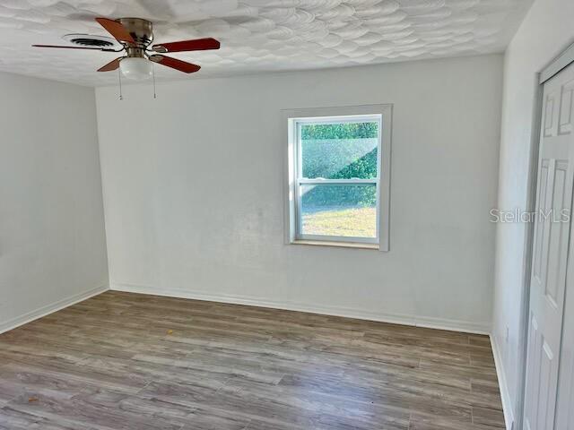 empty room featuring ceiling fan, a textured ceiling, and hardwood / wood-style flooring