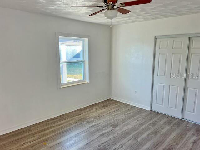 unfurnished room with ceiling fan, light hardwood / wood-style flooring, and a textured ceiling