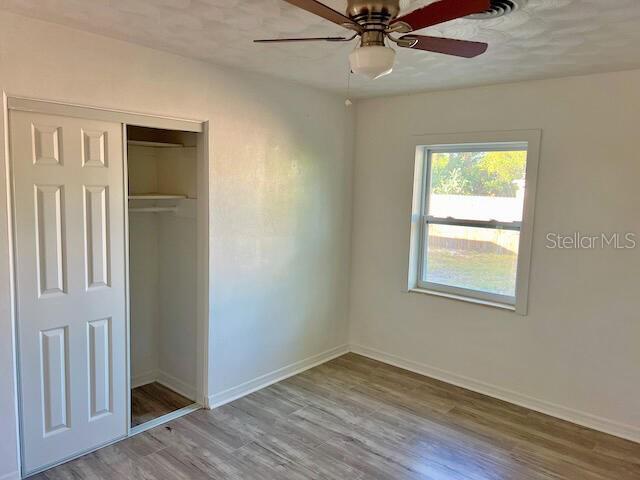 unfurnished bedroom with ceiling fan, a closet, and light hardwood / wood-style floors