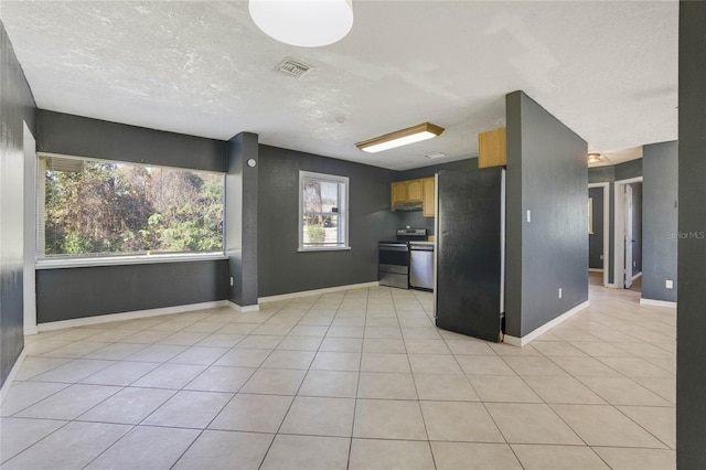 kitchen with light tile patterned flooring, a textured ceiling, and appliances with stainless steel finishes