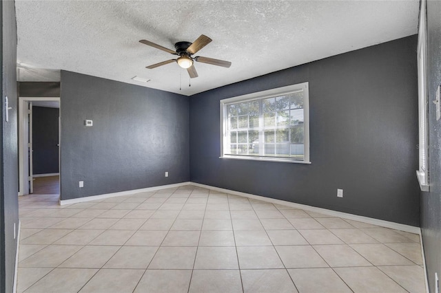 tiled empty room featuring ceiling fan and a textured ceiling