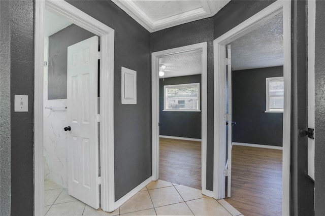 corridor with light tile patterned floors, crown molding, and a textured ceiling