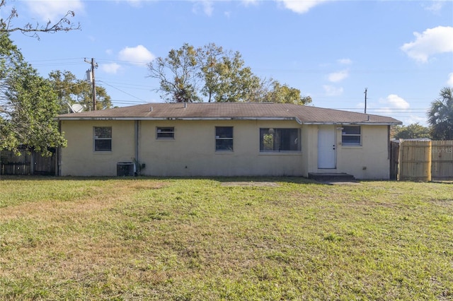 back of house featuring a lawn and central air condition unit