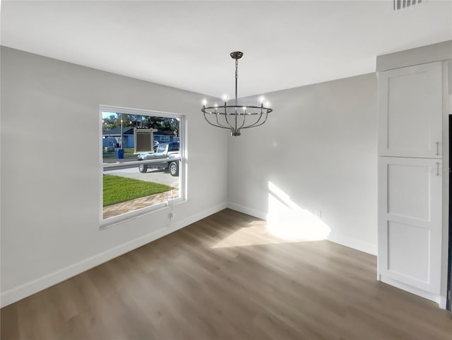 unfurnished dining area with hardwood / wood-style floors and a notable chandelier