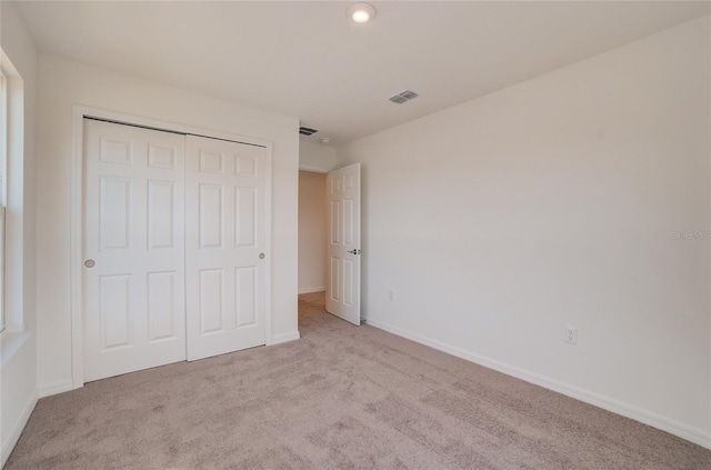 unfurnished bedroom with light carpet and a closet