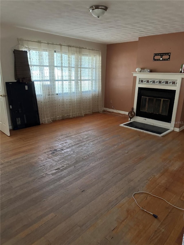 unfurnished living room featuring a healthy amount of sunlight, wood-type flooring, and a textured ceiling