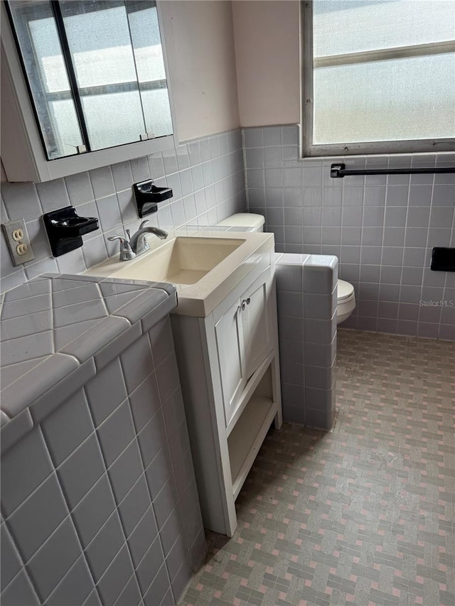 bathroom with vanity, tile walls, and toilet