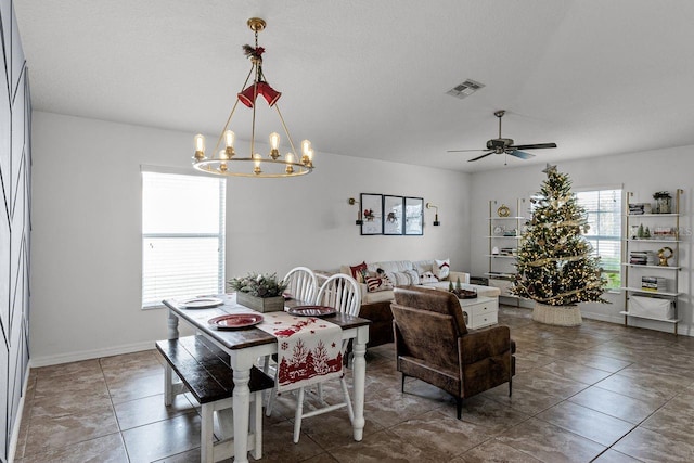 dining space featuring dark tile patterned flooring and ceiling fan with notable chandelier