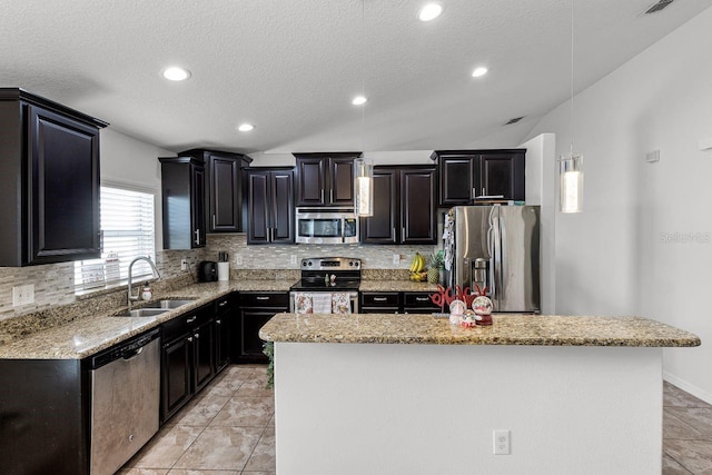 kitchen with backsplash, stainless steel appliances, sink, decorative light fixtures, and a center island