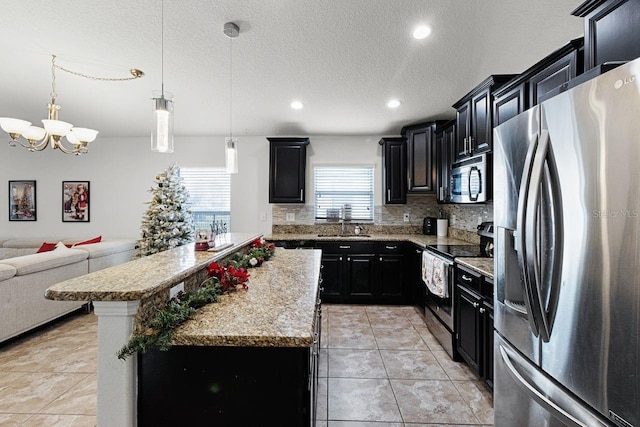 kitchen with tasteful backsplash, stainless steel appliances, sink, decorative light fixtures, and a center island