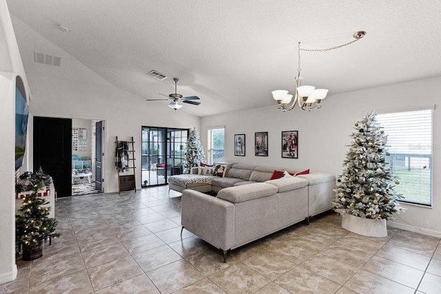 tiled living room featuring a textured ceiling, ceiling fan with notable chandelier, and vaulted ceiling