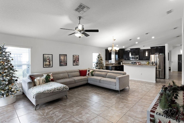 living room with ceiling fan with notable chandelier, light tile patterned flooring, lofted ceiling, and a textured ceiling