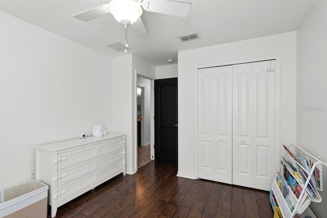 bedroom featuring a textured ceiling, dark hardwood / wood-style flooring, a closet, and ceiling fan