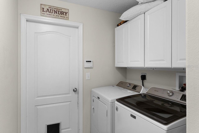 laundry area with washer and clothes dryer, cabinets, and a textured ceiling