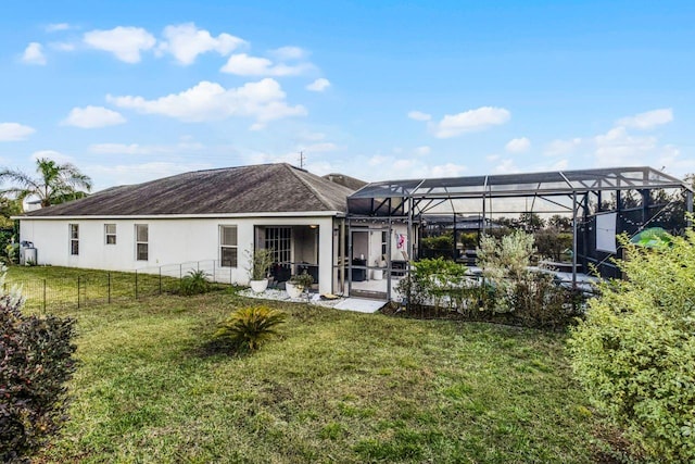 back of property featuring glass enclosure and a yard