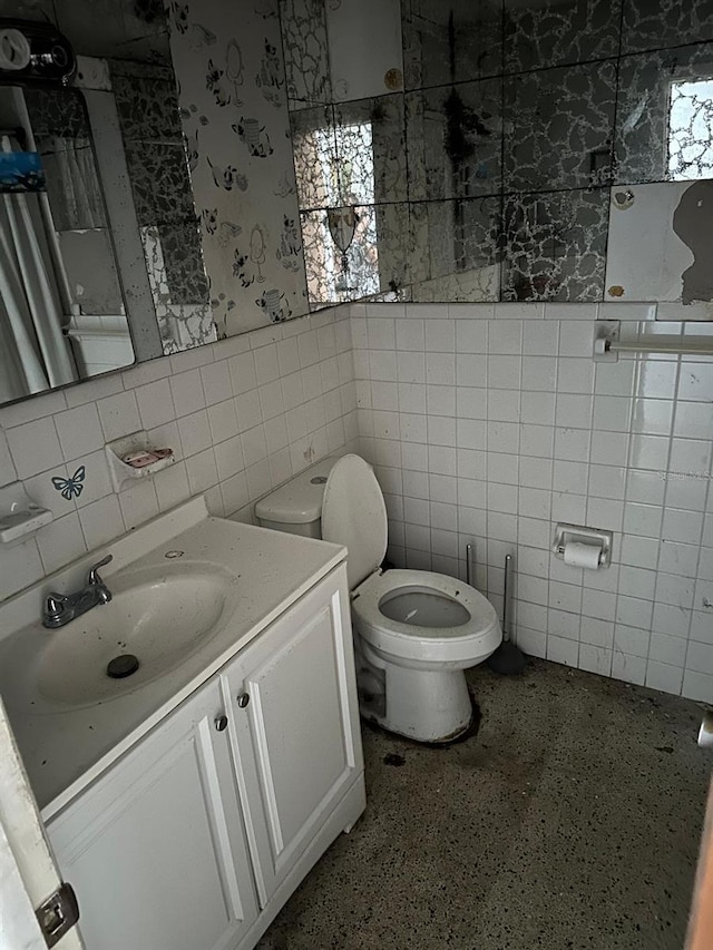 bathroom featuring vanity, toilet, and tile walls