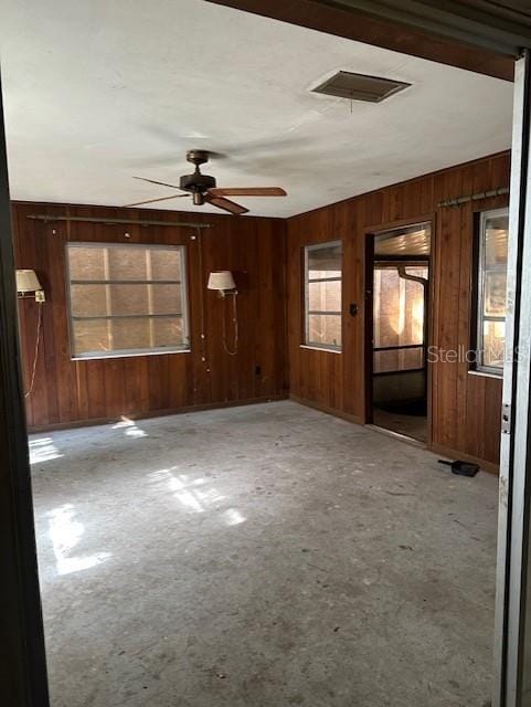 empty room with ceiling fan and wooden walls