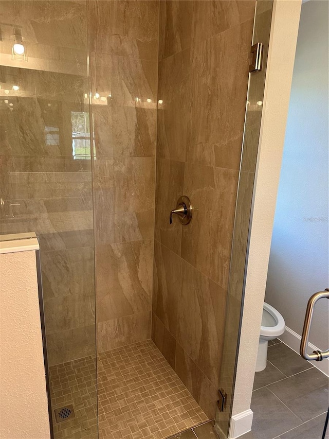 bathroom featuring tile patterned floors, toilet, and a shower with shower door