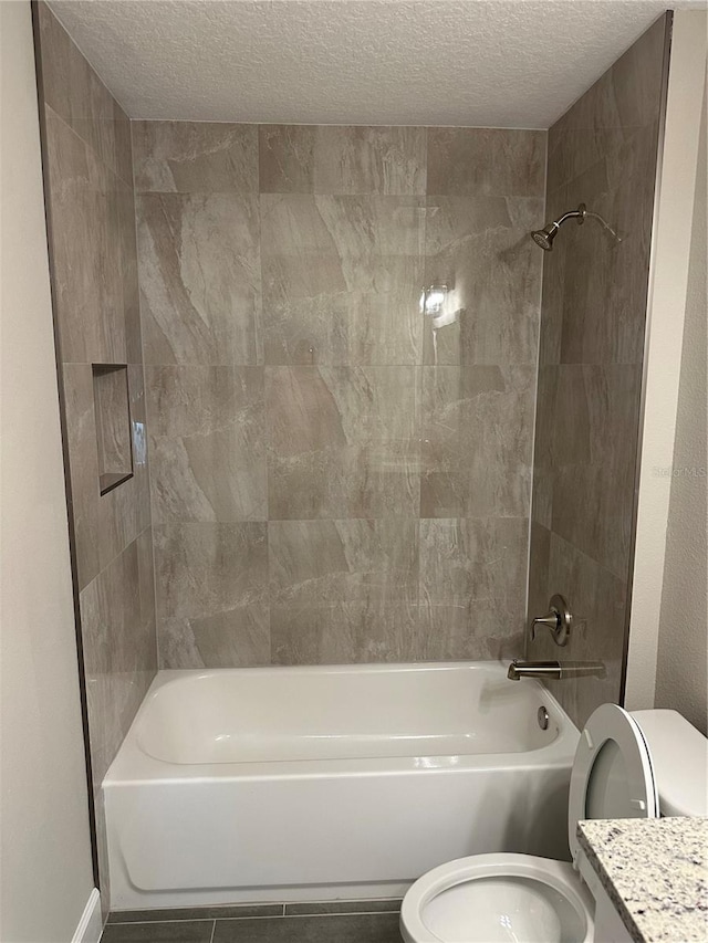 full bathroom with vanity, tiled shower / bath combo, a textured ceiling, and toilet