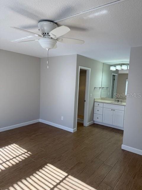 unfurnished bedroom with a textured ceiling, ceiling fan, dark wood-type flooring, and sink