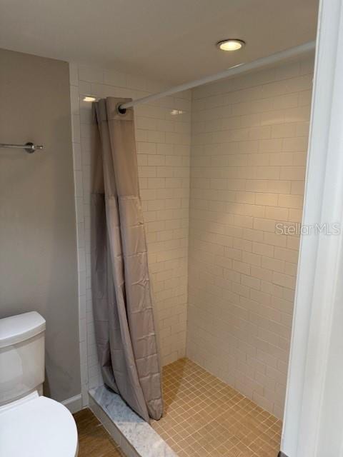 bathroom with a shower with shower curtain and toilet