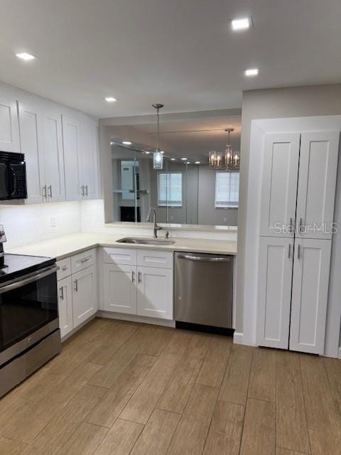 kitchen with an inviting chandelier, sink, decorative light fixtures, white cabinetry, and stainless steel appliances