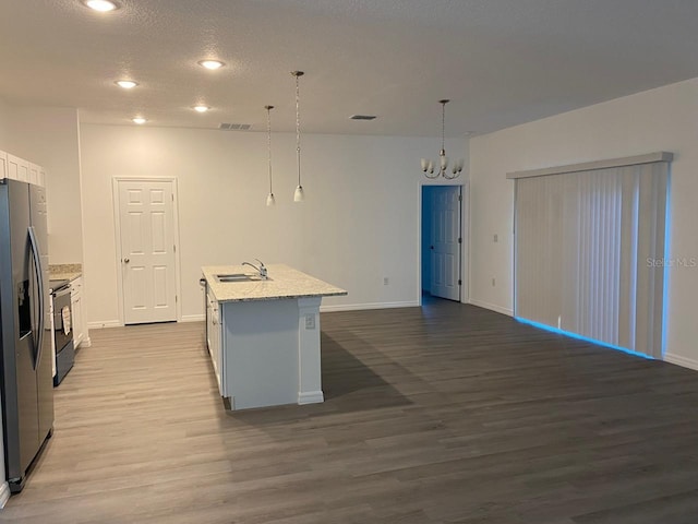 kitchen featuring white cabinets, pendant lighting, a kitchen island with sink, and sink