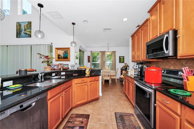 kitchen featuring sink, hanging light fixtures, stainless steel appliances, dark stone countertops, and lofted ceiling