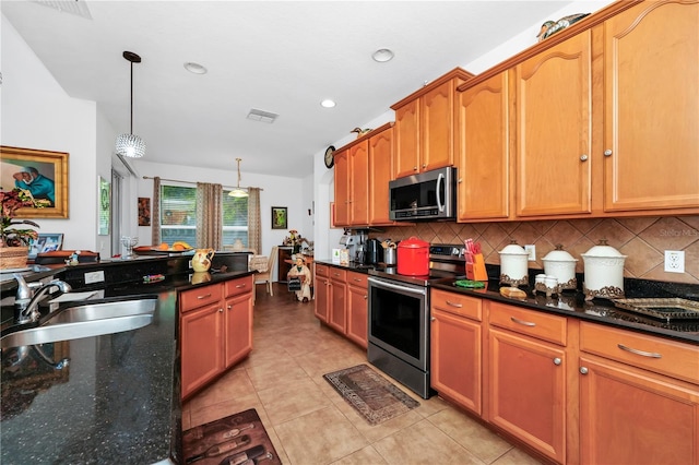 kitchen featuring appliances with stainless steel finishes, backsplash, dark stone counters, sink, and decorative light fixtures