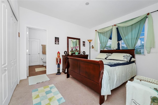 carpeted bedroom with ensuite bathroom and a closet