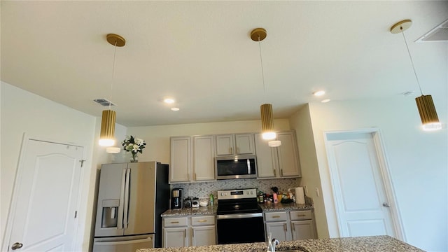 kitchen with hanging light fixtures, decorative backsplash, gray cabinets, light stone countertops, and appliances with stainless steel finishes