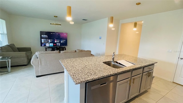 kitchen with pendant lighting, a center island with sink, sink, stainless steel dishwasher, and light stone countertops