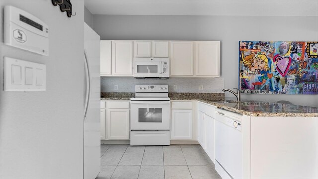 kitchen with white appliances, tasteful backsplash, white cabinetry, and dark stone counters