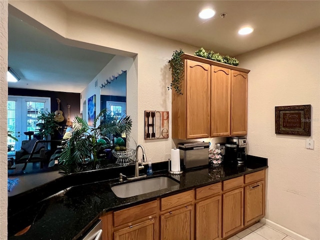 kitchen with light tile patterned floors, sink, and dark stone counters