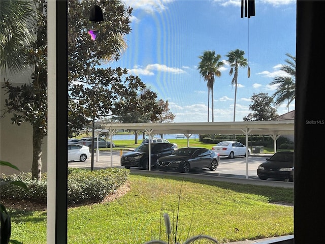 view of parking / parking lot featuring a carport and a lawn