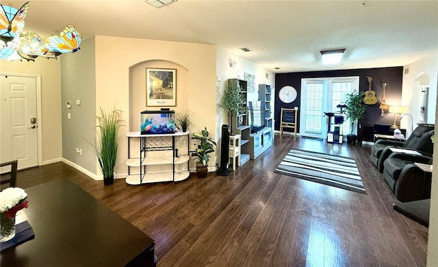 entryway featuring baseboards, a textured ceiling, arched walkways, and wood finished floors