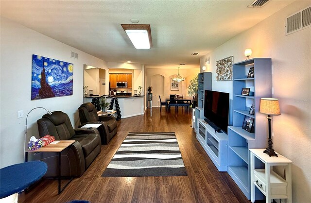 living room featuring dark wood-style floors, visible vents, and a textured ceiling