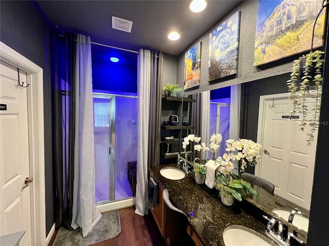 bathroom featuring wood finished floors, a stall shower, a sink, and visible vents