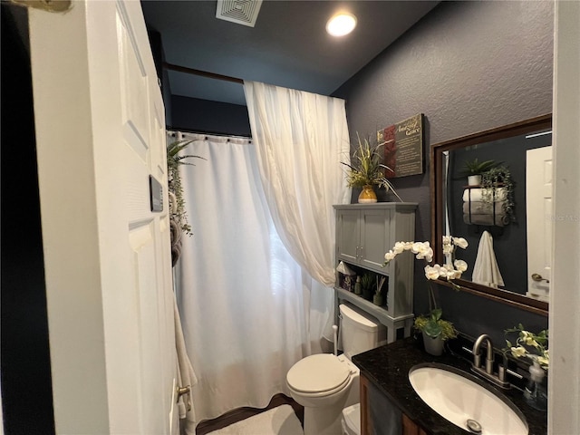 bathroom featuring visible vents, a textured wall, a shower with shower curtain, toilet, and vanity