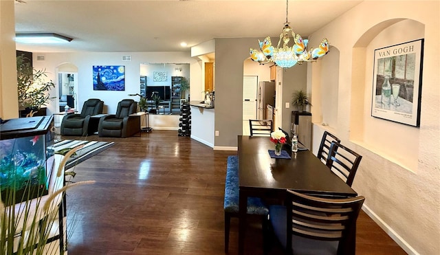 dining room featuring dark wood-style floors, baseboards, and an inviting chandelier