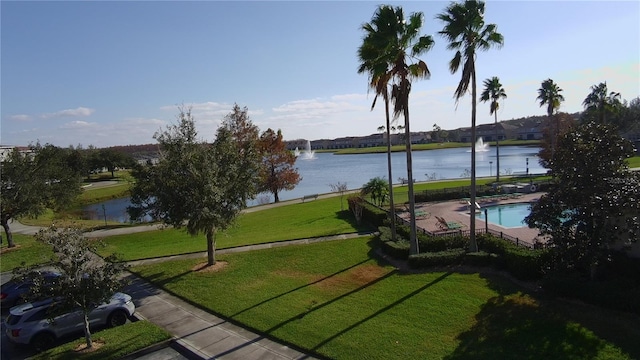 surrounding community with a water view and a lawn